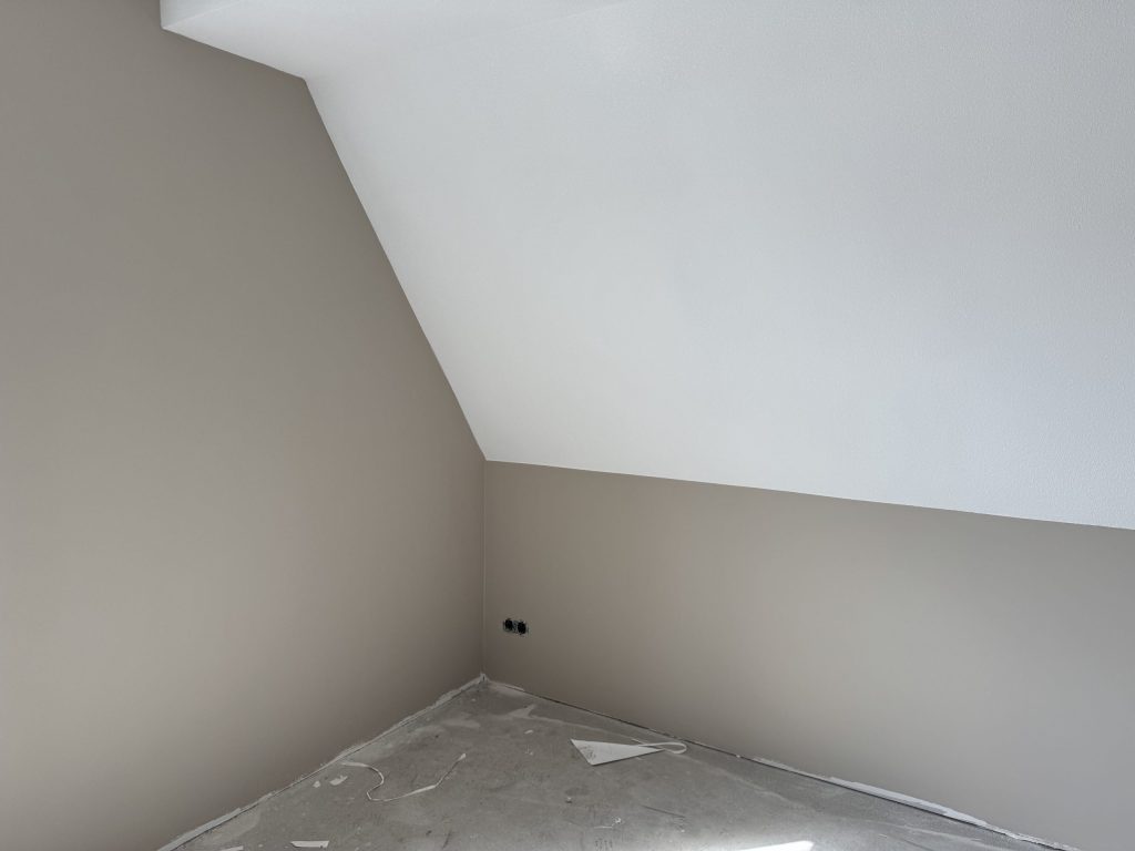 Zolderkamer met een schuine wand en egaal afgewerkte grijze muren